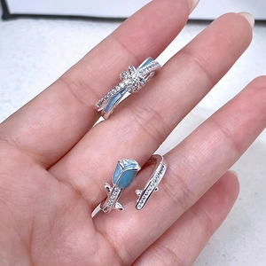 Détail de bagues fleurs et papillons en émail bleu argentées avec pierres zircon