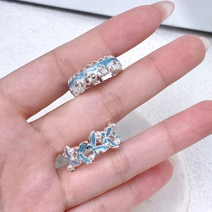Détail de bagues fleurs et papillons en émail bleu clair avec perles et bords en dentelle