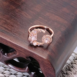 Dettaglio anello luna oro rosa con stella rosa, perla bianca e zirconi micro-incastonati