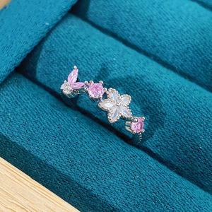 Macro detail of pink zircon butterfly and crystal flower ring on velvet