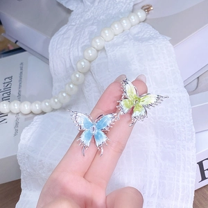 Détail des bagues papillon en émail avec dégradé de bleu et vert sur le doigt