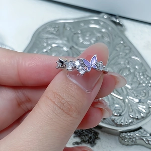 Detail of silver butterfly ring with purple enamel and zircon stones on a hand