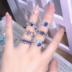 Dettaglio di anelli sovrapponibili in argento con zirconi blu mare e trasparenti micro-pave