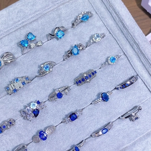 Dettaglio di vari anelli d'argento con zirconi blu in una scatola di velluto