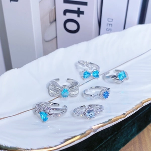 Dettaglio del set di anelli in argento con zirconi blu e motivi floreali su vassoio in ceramica