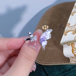 Dettaglio di un anello a farfalla in smalto viola con zircone a forma di cuore brillante