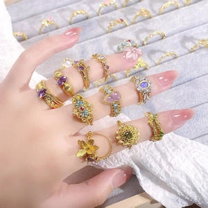Detailed shot of retro enamel rings with zircon insets on fingers over lace fabric