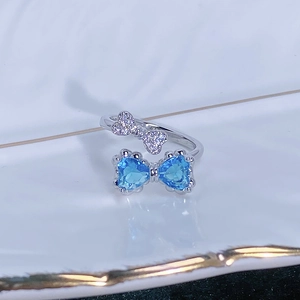 Dettaglio macro dell'anello d'argento con cuori blu e design a fiocco scintillante