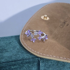 Dettaglio macro di fiori in smalto viola e cristalli lucenti su anello in argento