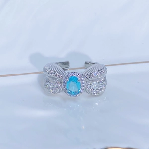 Dettaglio di un anello a fiocco in argento con gemma azzurra e pavé di zirconi bianchi