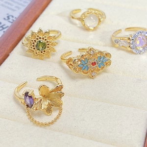 Detailed set of five vintage gold rings with enamel and colorful gemstones in a velvet box