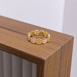 Detailed close-up of a vintage golden flower ring with pink enamel on a wooden display