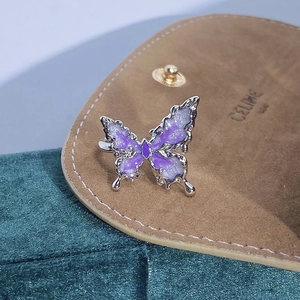 Vista dettagliata dell'anello a farfalla in smalto glitter viola su sfondo di camoscio