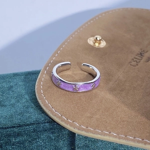Dettaglio dell'anello aperto in smalto viola con rilievi floreali dorati su pelle