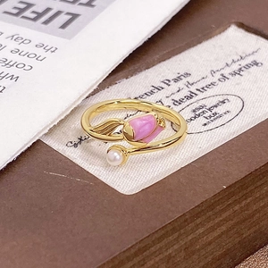 Detail of a gold tulip ring with pink enamel and a white pearl in a warm vintage setting