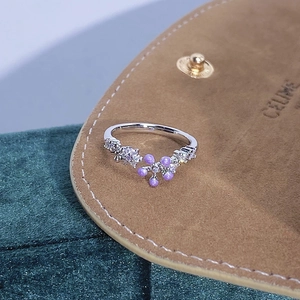 Dettaglio anello fiore smalto viola con zirconi su sfondo di velluto verde