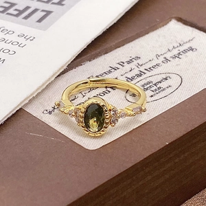 Detail shot of vintage gold ring with olive green stone and zircon accents