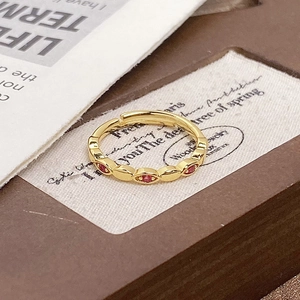 Macro shot of gold adjustable ring featuring red marquise zircon and vintage enamel details