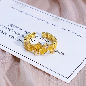 Macro detail of gold adjustable ring featuring yellow enamel flowers and small zircons