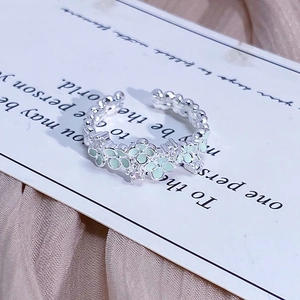 Close-up of adjustable silver ring with mint green enamel petals and zircon accents