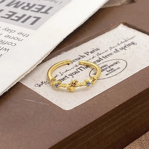 Macro detail of retro gold-plated open ring with star motif and blue zircon accents