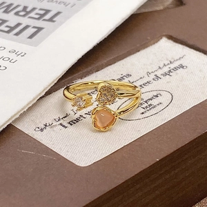 Close-up of gold heart ring with pink enamel and sparkling pavé zircon details