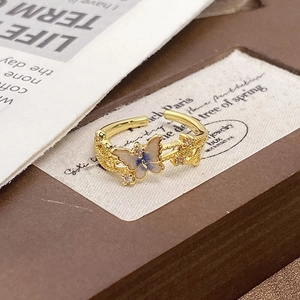 Macro detail of enamel butterfly and flower ring with zircon inlays and golden base