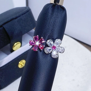 Makroaufnahme des Doppelblumenrings mit rosa und weißen Edelsteinen auf Lederhalter