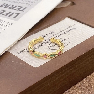 Macro shot of wavy gold ring with green and pink enamel and zircon inlay details