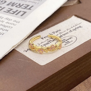 French retro gold vine ring with pink enamel roses on a vintage wooden background
