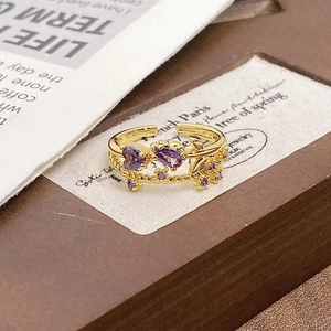 Detail of adjustable gold ring with purple heart and pear stones on vintage wood