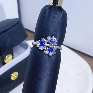 Detailansicht von silbernem Blumenring mit blauer Emaille auf einem Schmuckständer präsentiert
