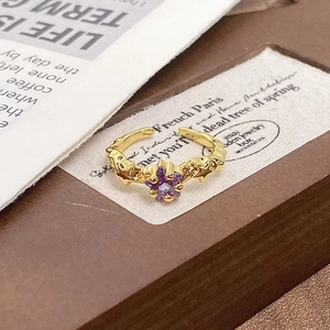 Macro shot of 18K gold open ring with purple star zircon and moon relief details