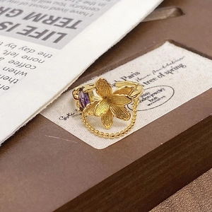 Detail showing vintage gold flower ring with purple gemstone and delicate beaded chain