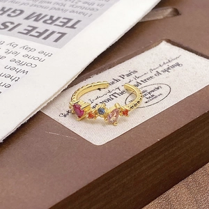 Close-up of vintage gold open ring with colorful zircon stones on textured background