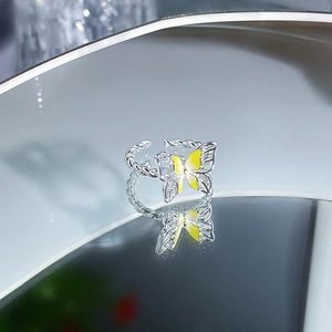 Detailansicht eines Silberrings mit gelbem Emaille-Schmetterling auf Spiegelfläche