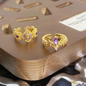 Détail de bagues rétro en émail avec fleurs, couronnes, pierres violettes et relief doré