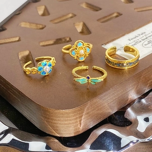 Détails de bagues dorées vintage avec motifs de fleurs et libellules en émail