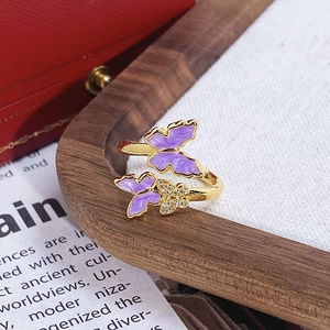 Détail d'une bague dorée avec papillons en émail violet et incrustation de zircons