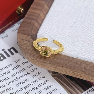 Gros plan d'une bague dorée vintage avec pierre verte carrée et texture dépolie