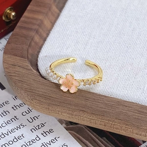 Détail d'une bague dorée vintage avec fleur rose, petites perles et zircons brillants