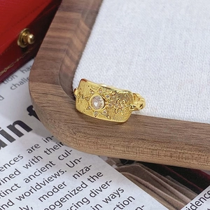 Détail d'une bague vintage dorée avec motif étoile rectangulaire et cristal central