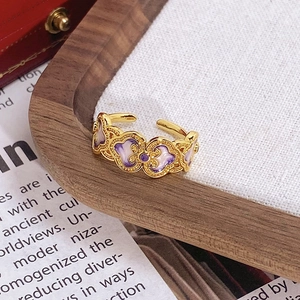 Vue macro d'une bague dorée vintage avec motifs fleurs en émail violet sur lin blanc