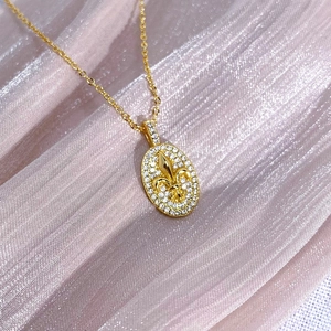 Detailansicht einer goldenen Iris-Halskette mit Zirkonia auf rosa gefaltetem Hintergrund