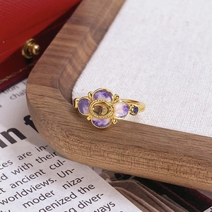 Gros plan d'une bague fleur vintage avec émail violet, ambre et finition dorée