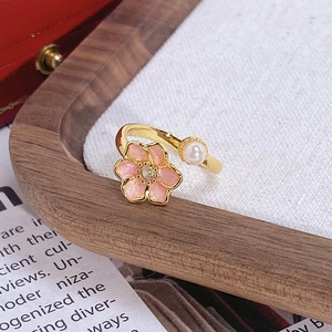 Gros plan d'une bague fleur rose avec perle et petit cristal sur plateau en bois