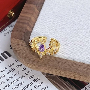 Détail d'une bague couronne dorée vintage avec pierre goutte violette et zircons