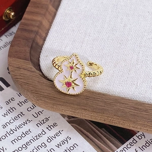 Vue détaillée d'une bague gourde dorée en émail blanc sertie de cristaux roses