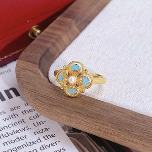Détails d'une bague trèfle vintage dorée avec émail bleu et incrustation de perle blanche