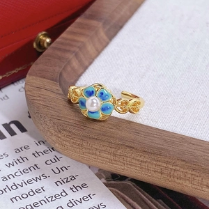 Détail d'une bague fleur en or vintage avec émail bleu et une perle blanche centrale